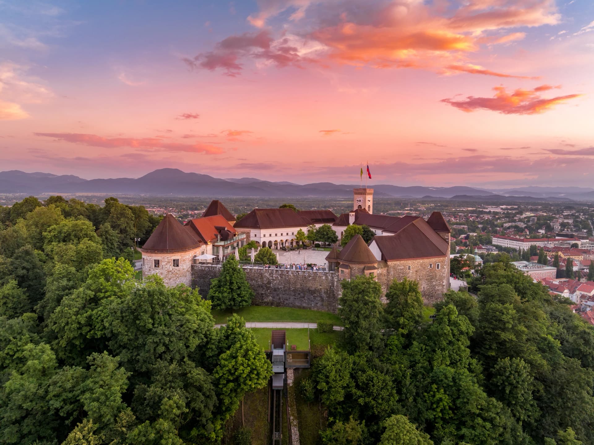 Aerial sunset view of Ljubljana castle in Slovenia , towers, bastions, funicular taking visitors up the hill with colorful sky