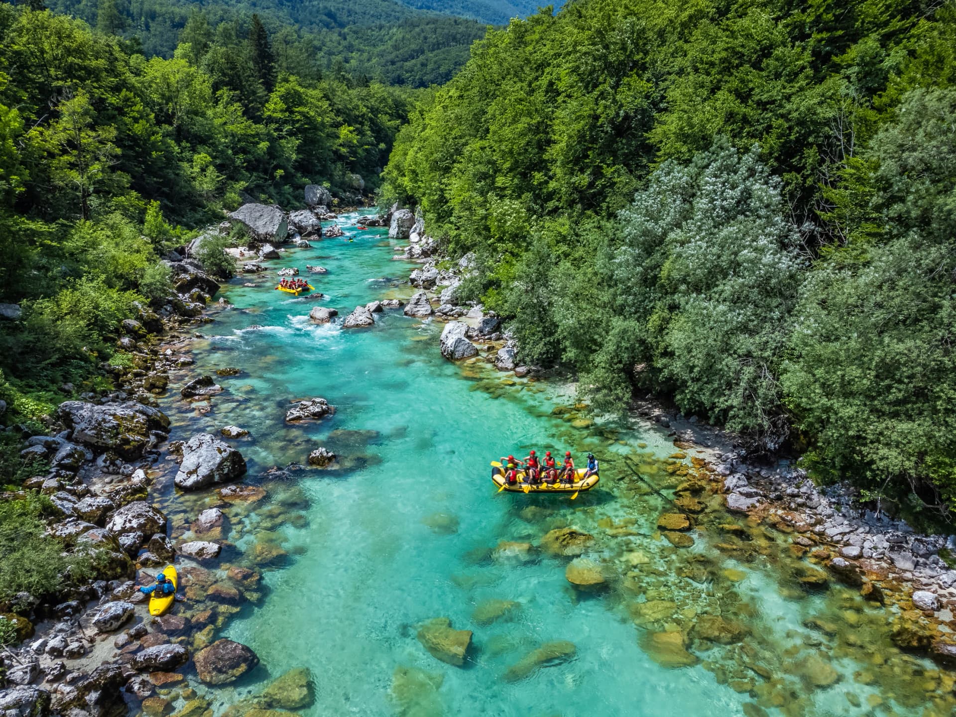 Soca Valley, Slovenia - Aerial view of the emerald alpine river Soca with rafting boats going down the river on a bright sunny summer day with green foliage. Whitewater rafting in Slovenia