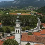 Luchtfoto van de stad Vipava, Slovenië. Rode daken, kerk, velden en met bos bedekte heuvels op de achtergrond
