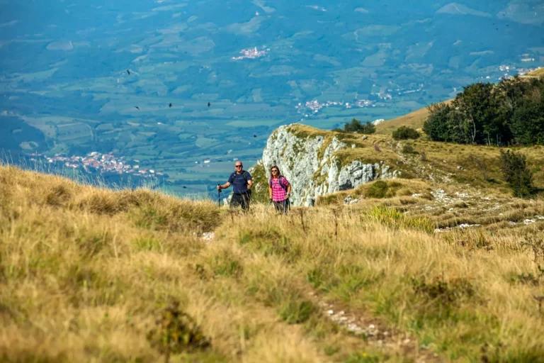 Bjergbestigerpar på vej op ad Nanos-plateauet i Slovenien med udsigt over Vipava-dalen